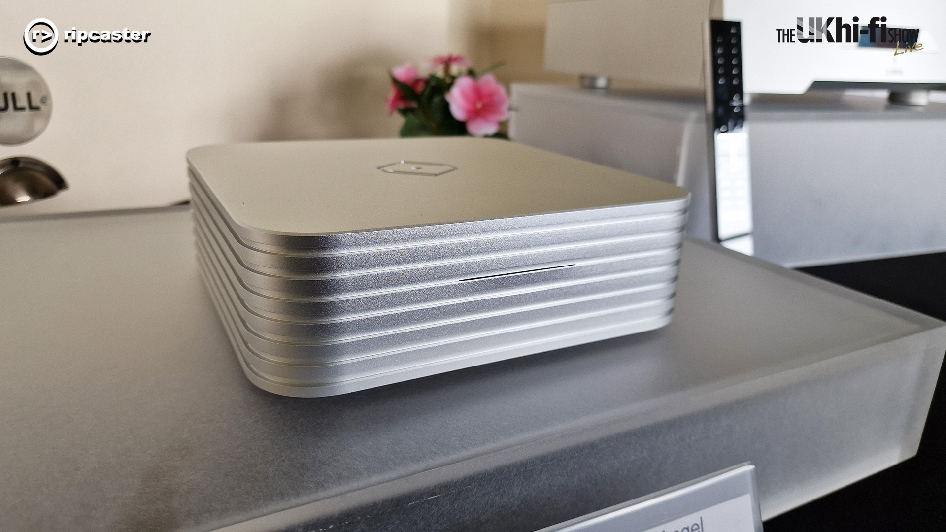 A small silver HiFi unit with a remote control in the background