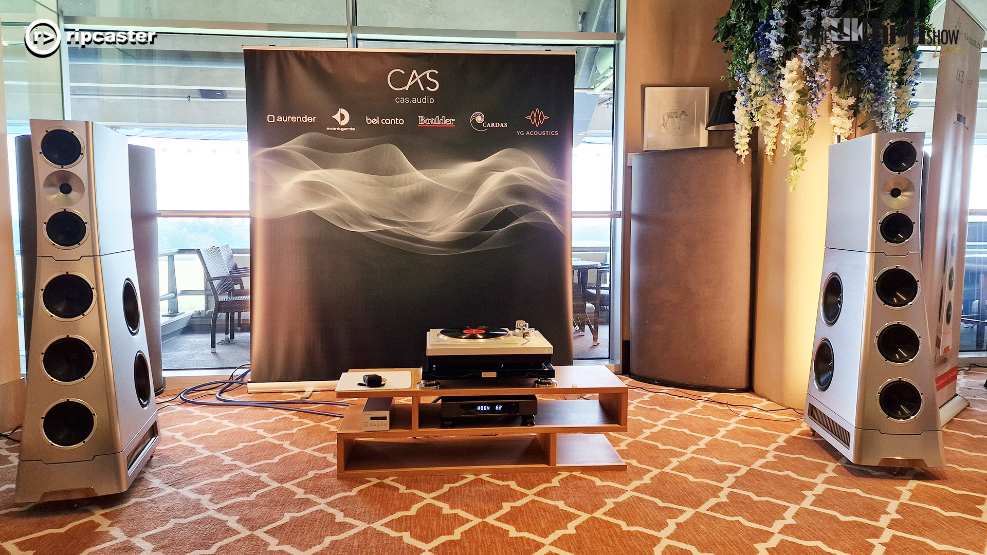 A pair of large silver speakers with HiFi equipment between them.