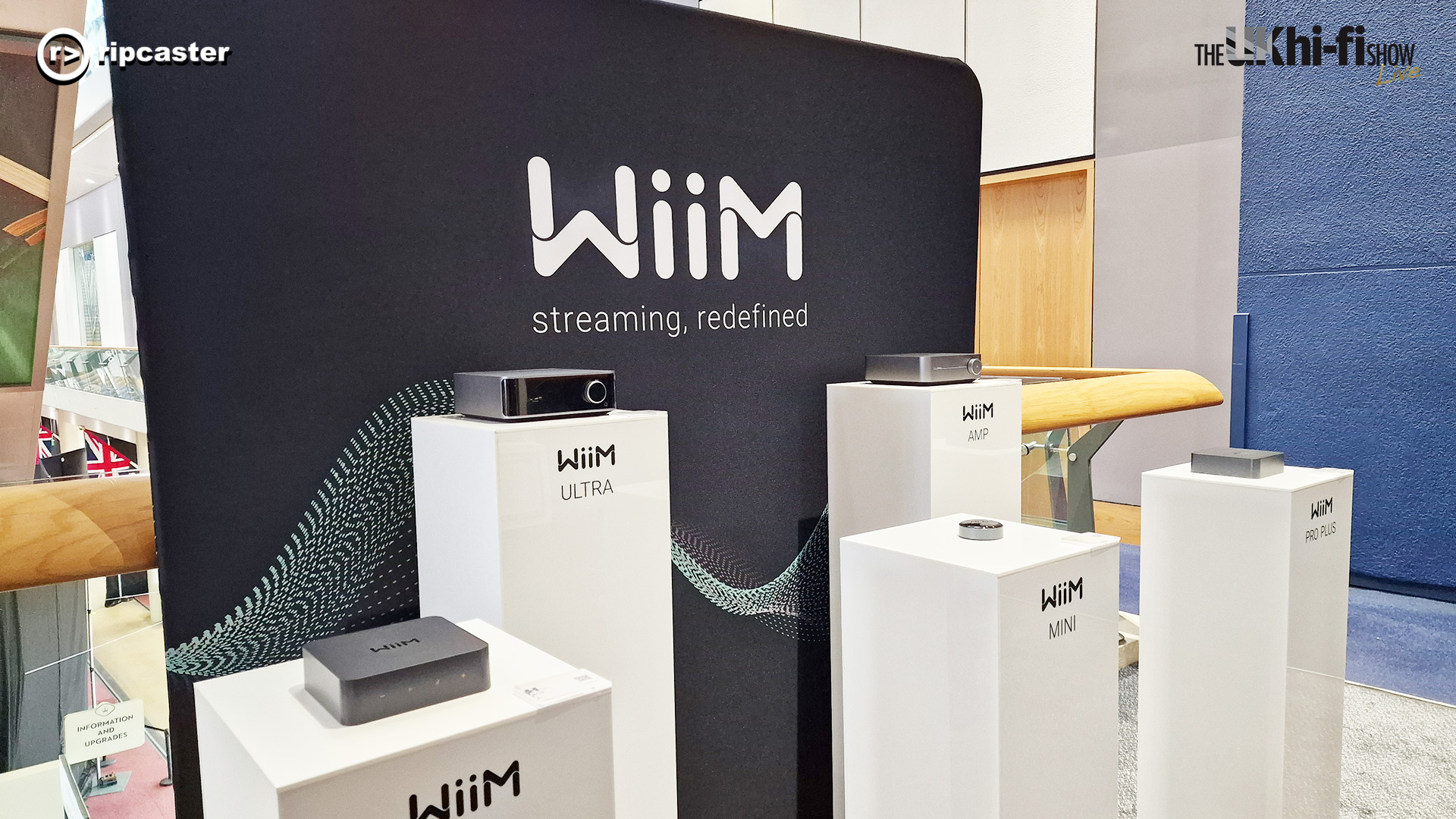 The WiiM stand with various pieces of WiiM equipment on tall white stands