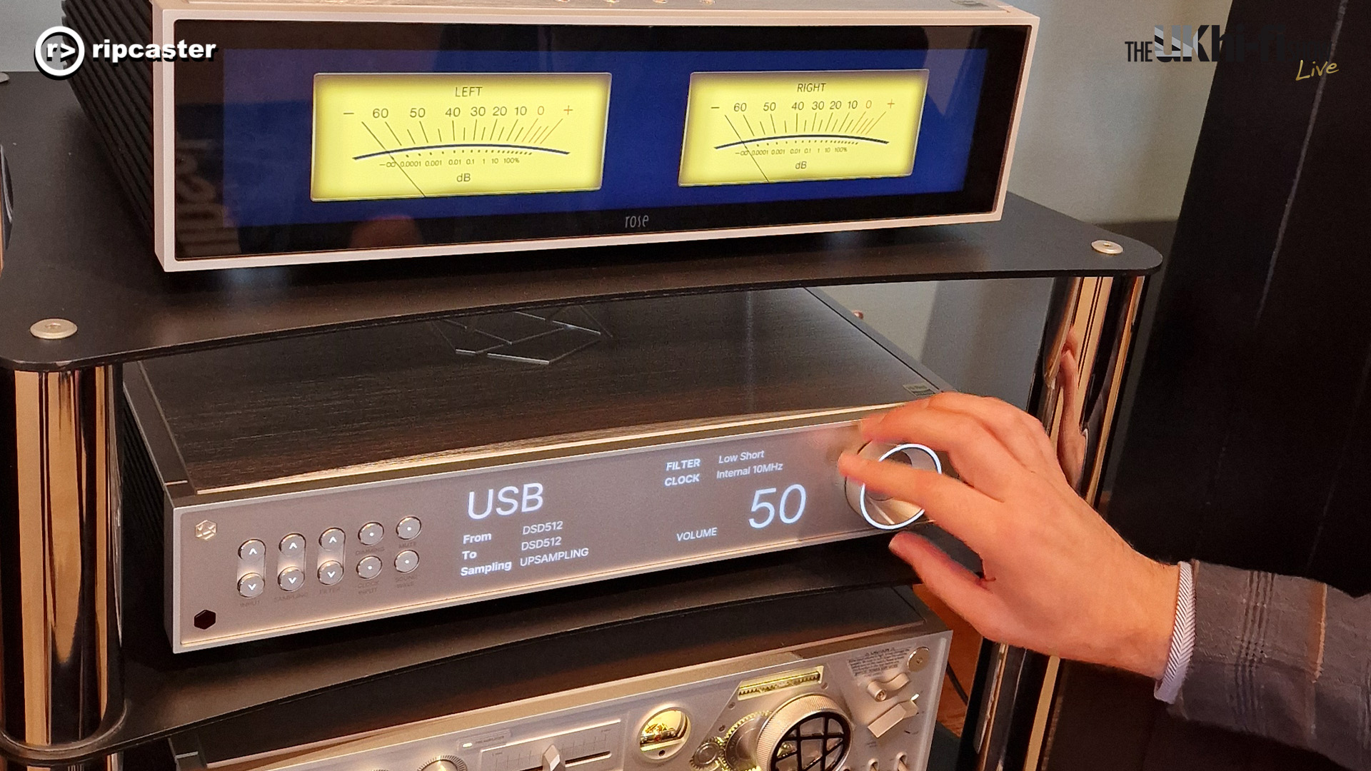 A man's hand turning the dial on a piece of HiFi Rose equipment