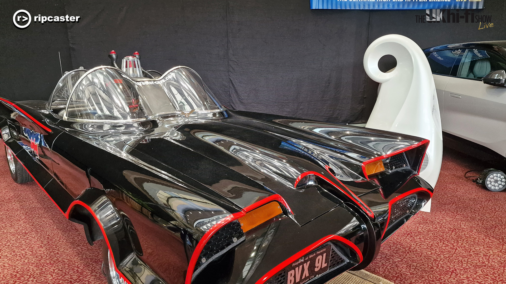 An old Batmobile with a white speaker beside it