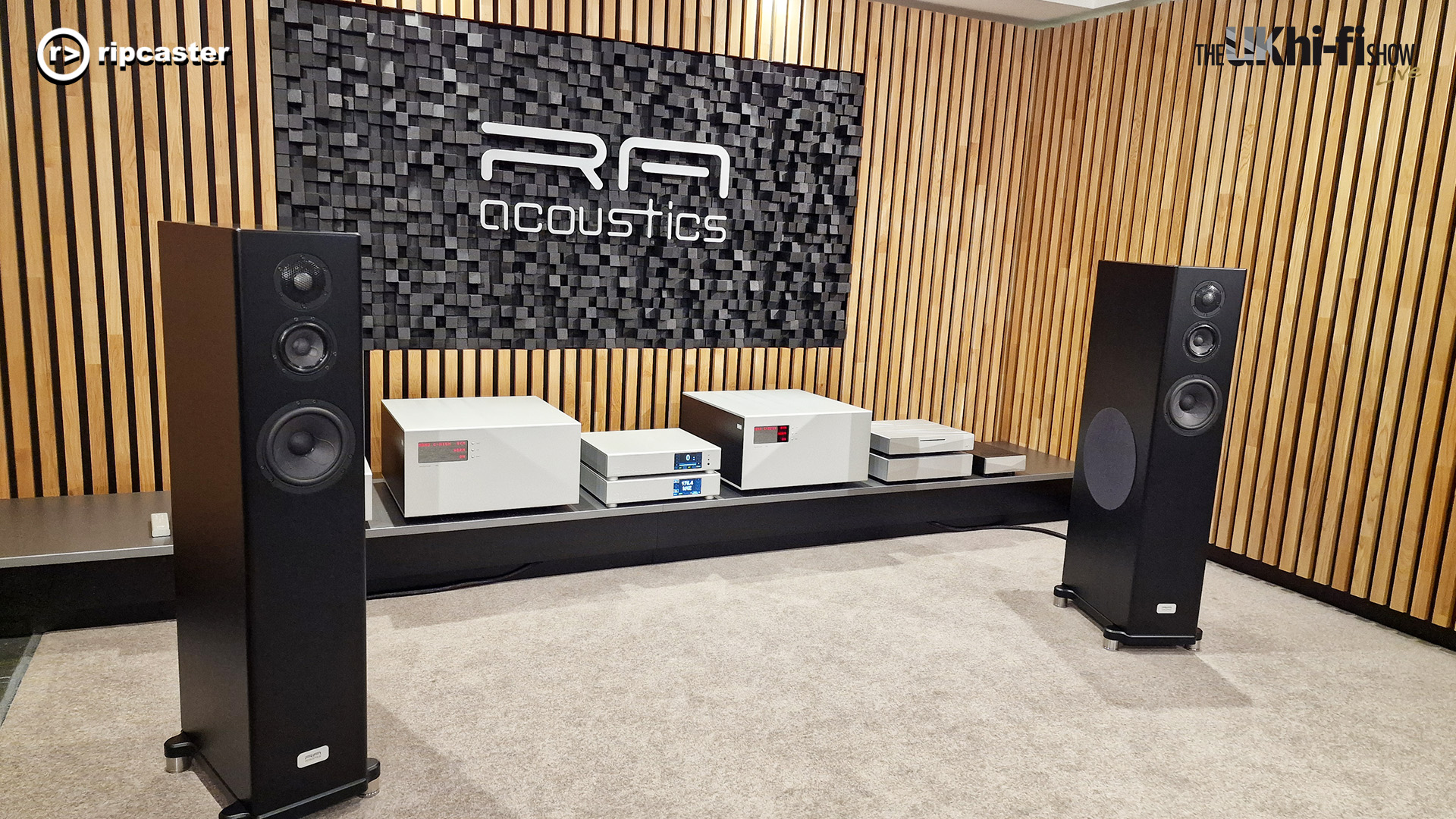 A pair of black floorstanding speakers either side of various pieces of HiFi equipment