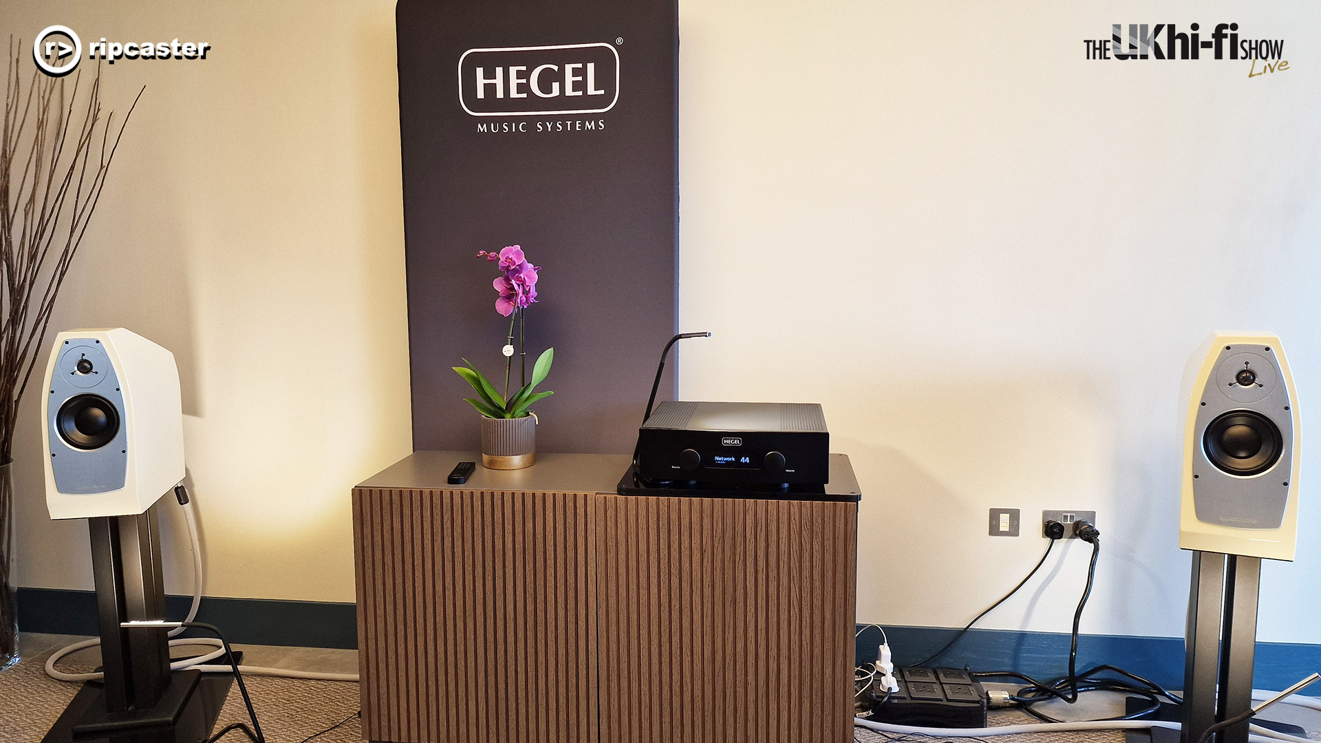 A pair of speakers on stands either side of a piece of HiFi equipment.