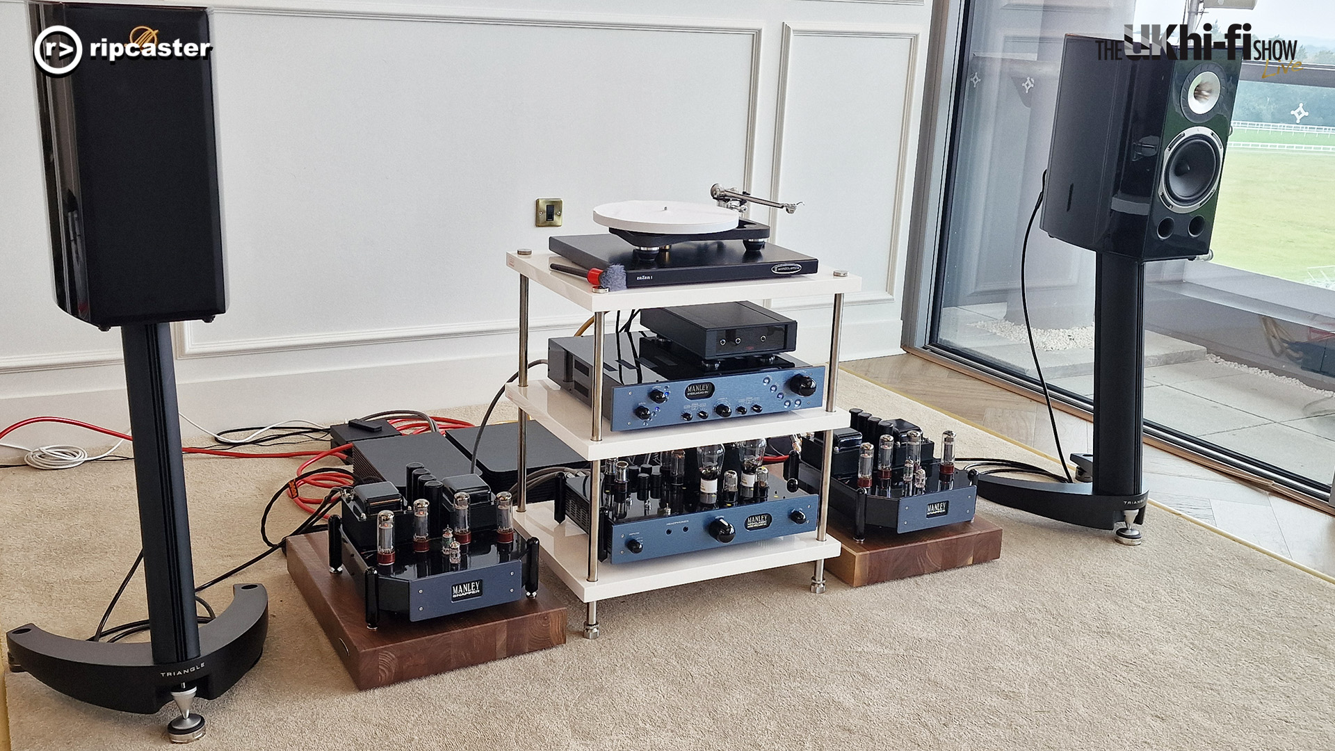 A pair of black bookshelf speakers on stands either side of HiFi equipment