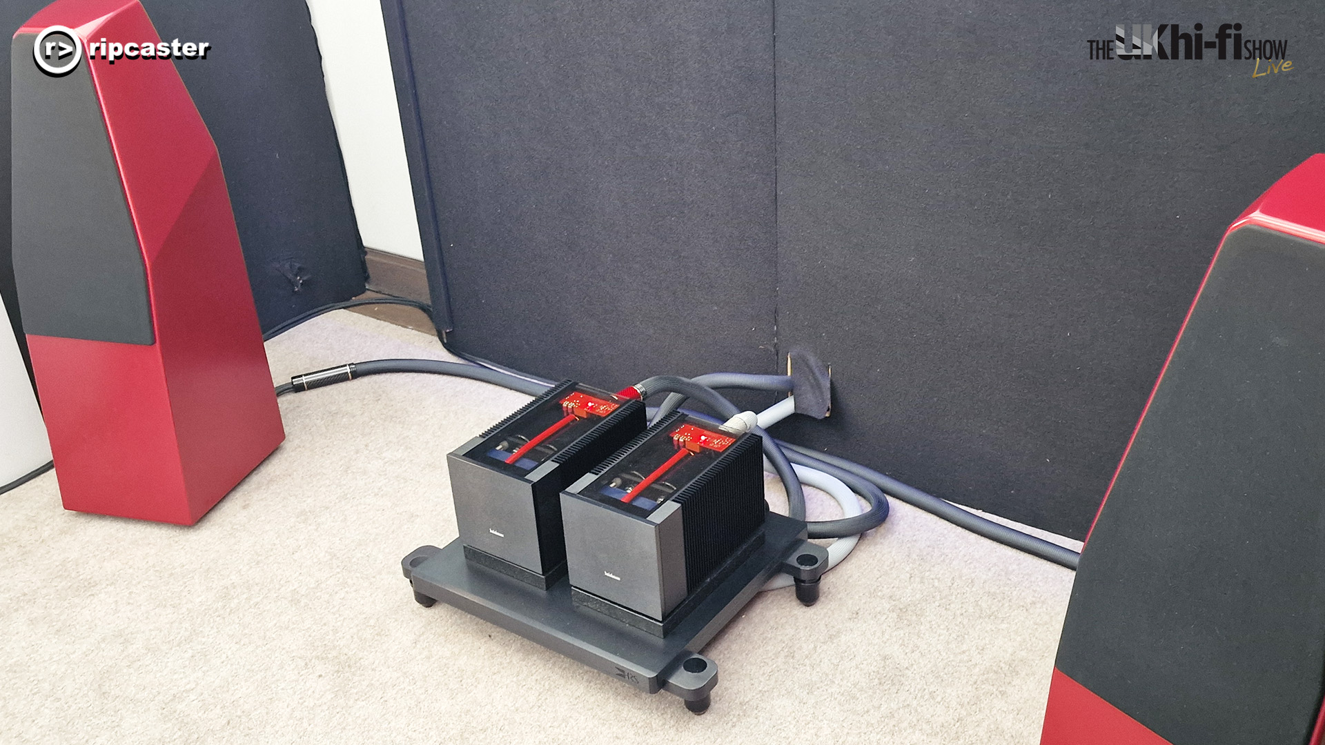 A pair of red and black blocks between two red floorstanding speakers