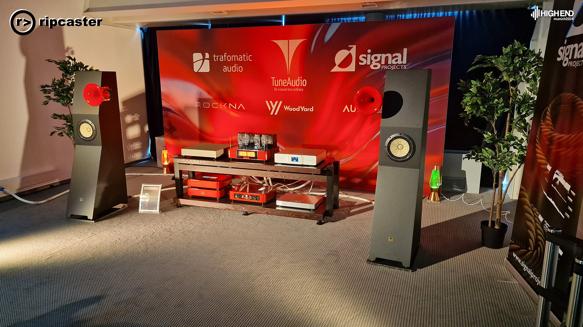 A pair of floorstanding speakers with small red funnels on the side.  Other HiFi equipment is between them.