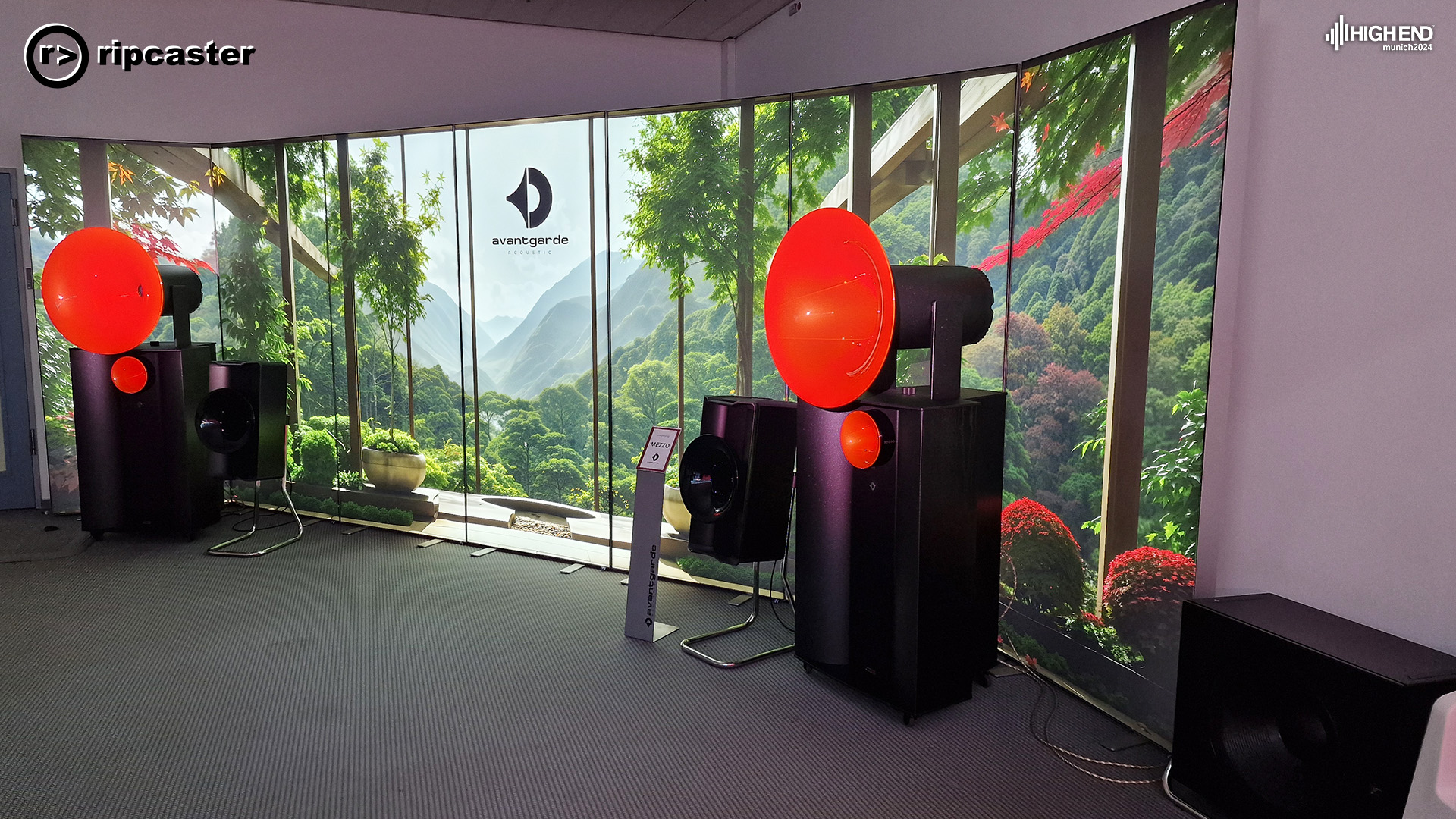 A pair of black speakers with red funnels on the top of them and large forest vista behind