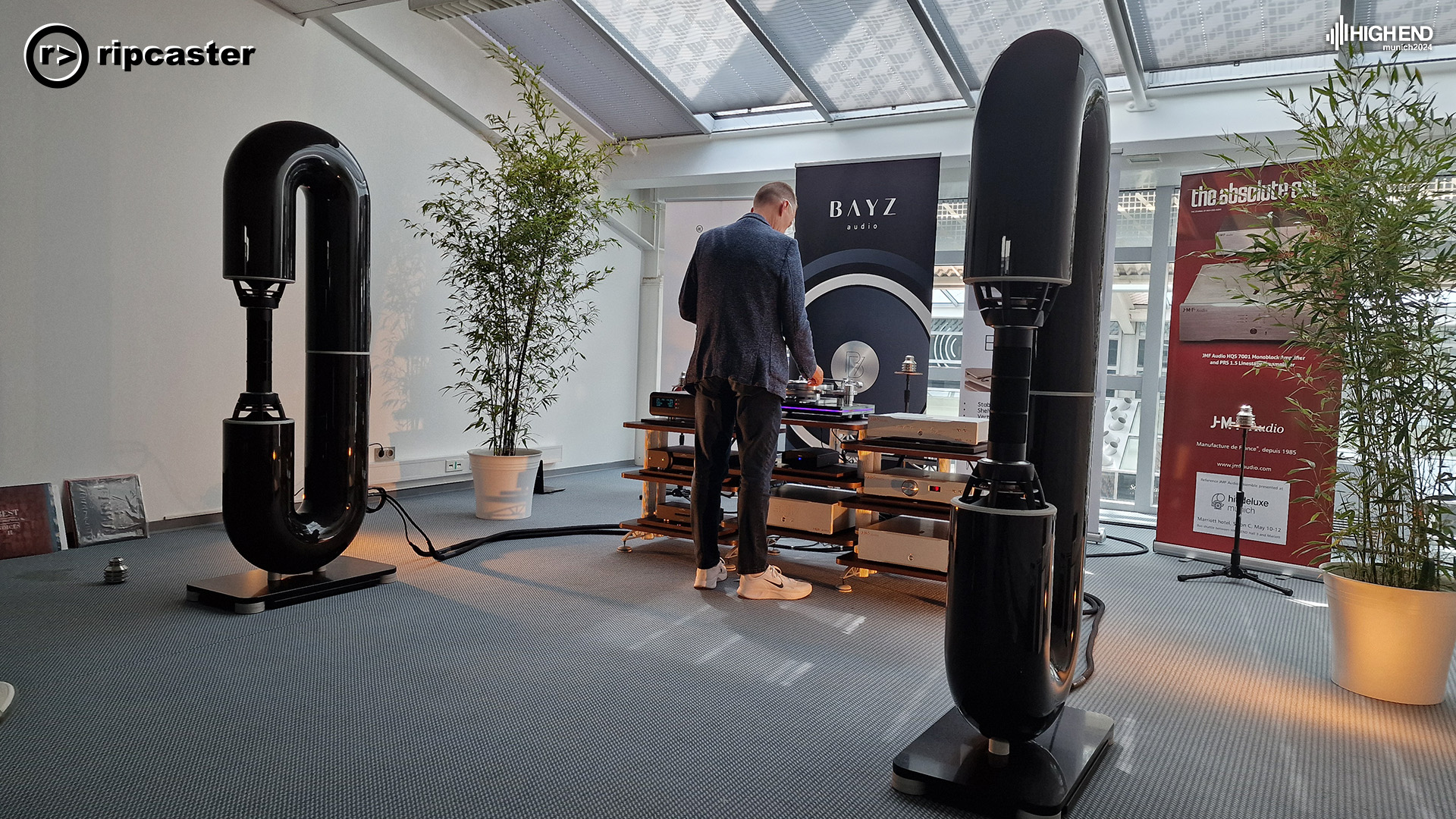 Speakers that look like they're made from big drainpipes bent into a letter C.  A man in between them changing a record.