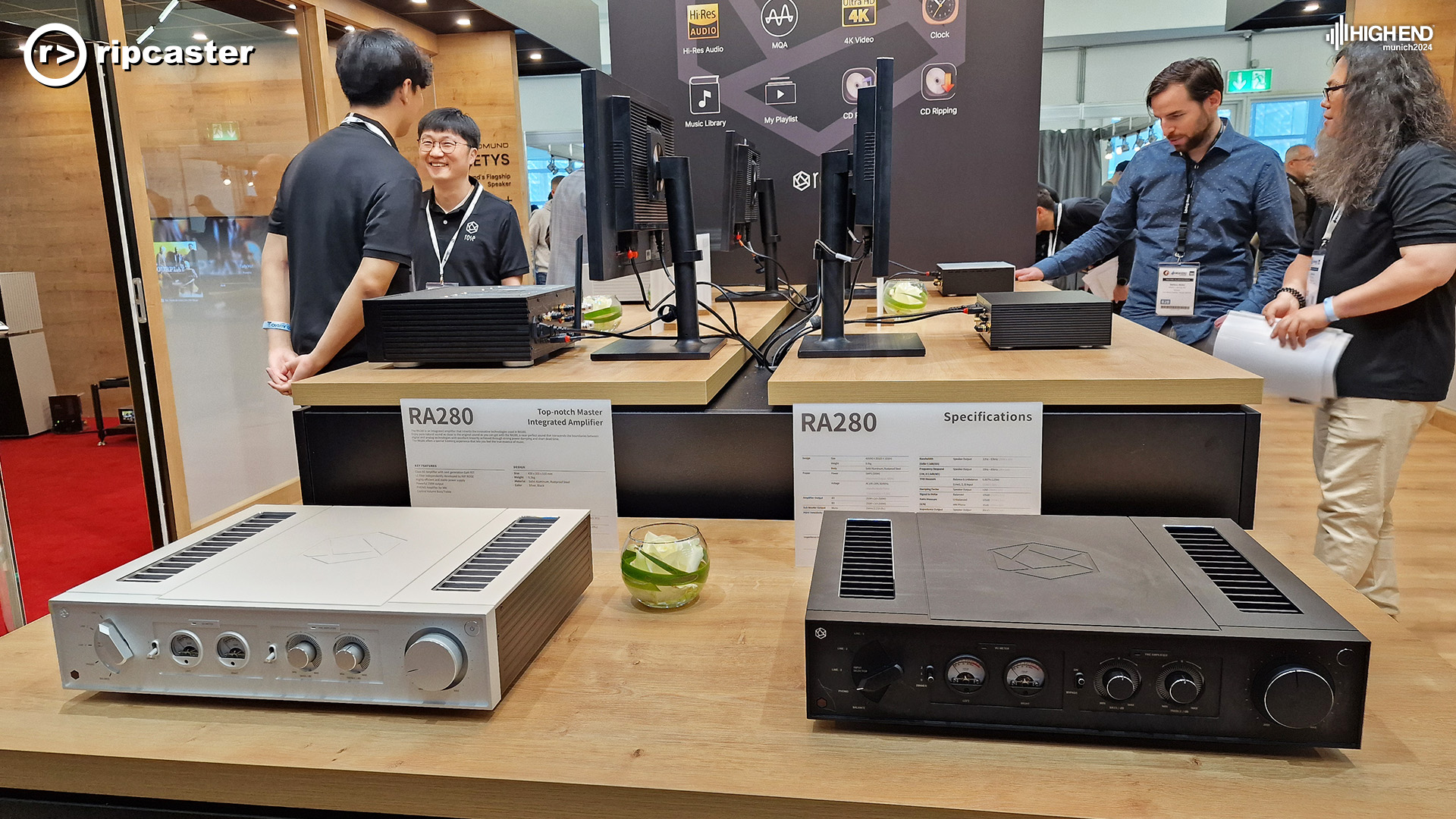 Four men in the background with HiFi Rose equipment on wooden tables.