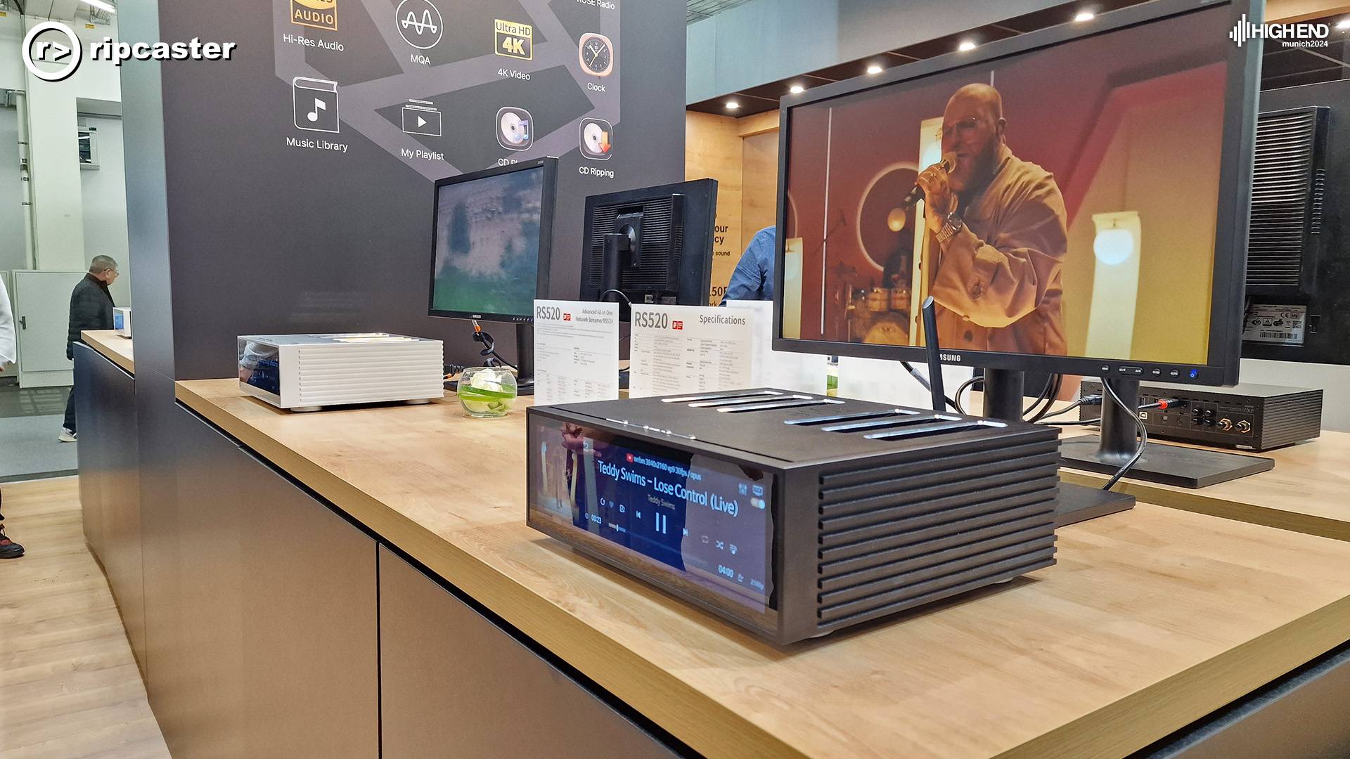 HiFi Rose equipment on a wooden stand.  An image of a man singing on a monitor.