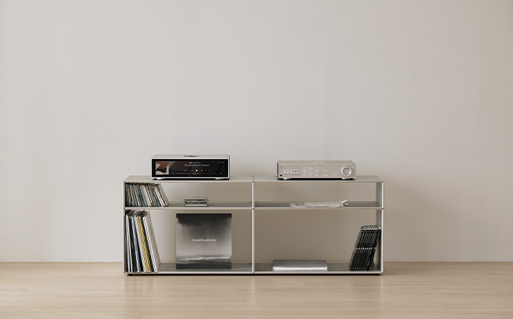 A shelving unit with albums on the bottom shelf.  On the top of the unit is the HiFi Rose RD160 and the RS130..  There are no cables visible.