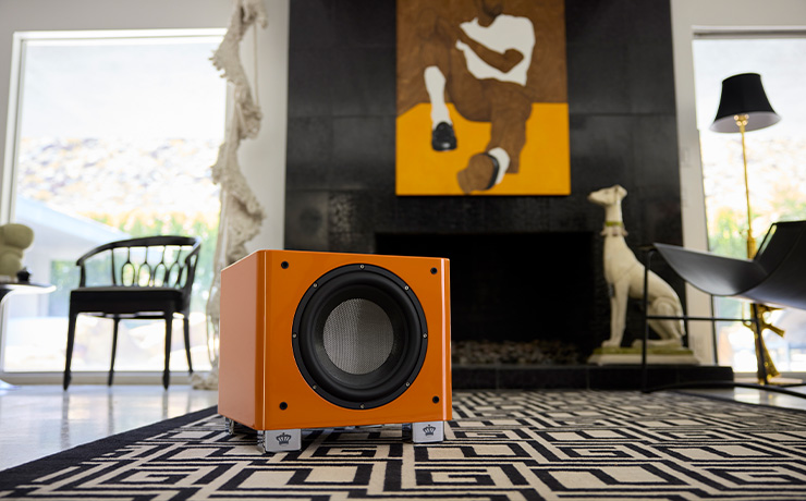 The REL T/9x Special Edition in orange on a cream and white geometric rug in a modern living space