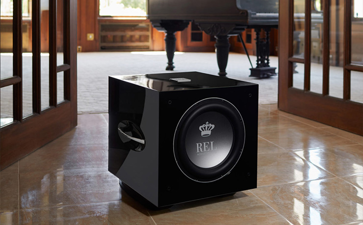 REL S/812 on a tiled floor with a piano behind