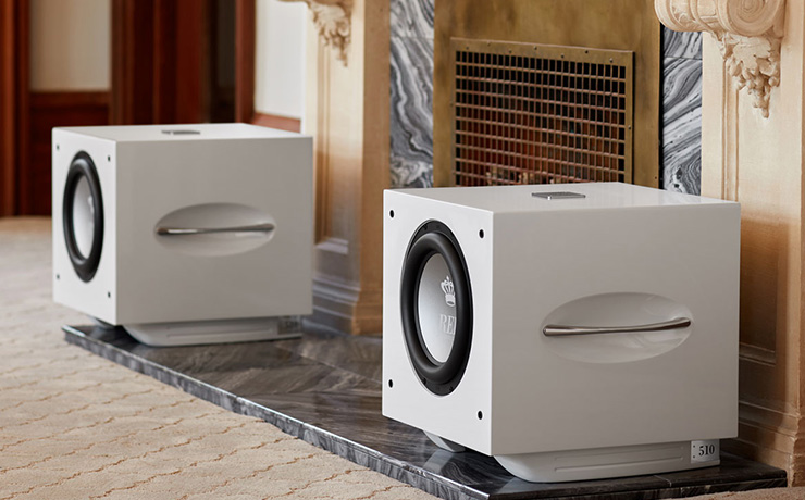 A pair of white REL S510s either side of a fireplace
