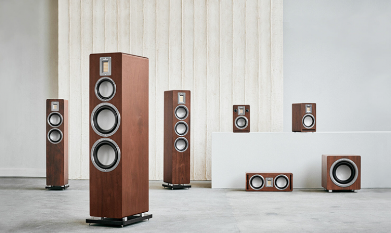 Audiovector QR series speakers spaced out in a large room.  The speakers are all dark walnut.  The room is light grey.