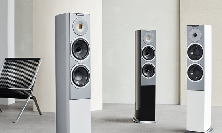 Audiovector R3 series speakers.  One each of Arreté, Avantgarde and Signature in a large space with a chair.