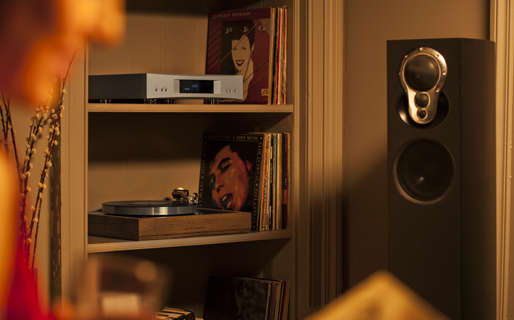Linn Akubarik Loudspeaker in a living room beside a set of shelves with vinyl, an LP12 and a DSM.