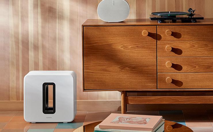 Sonos Sub Gen 4 in white on the floor beside a wooden sideboard