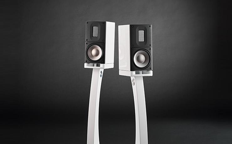 A pair of white Raidho Acoustic speakers on a very dark background