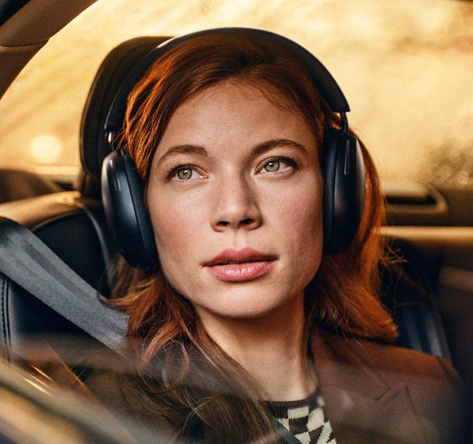 Sonos Ace Headphones in black on the head of a woman in a car