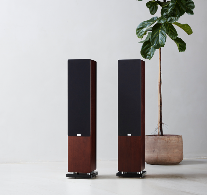 Audiovector QR5 a pair of dark walnut speakers with grilles beside a tall houseplant.