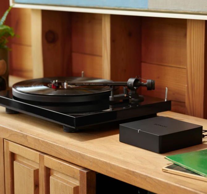 SONOS Port on a wooden unit with a record player to the left of it.