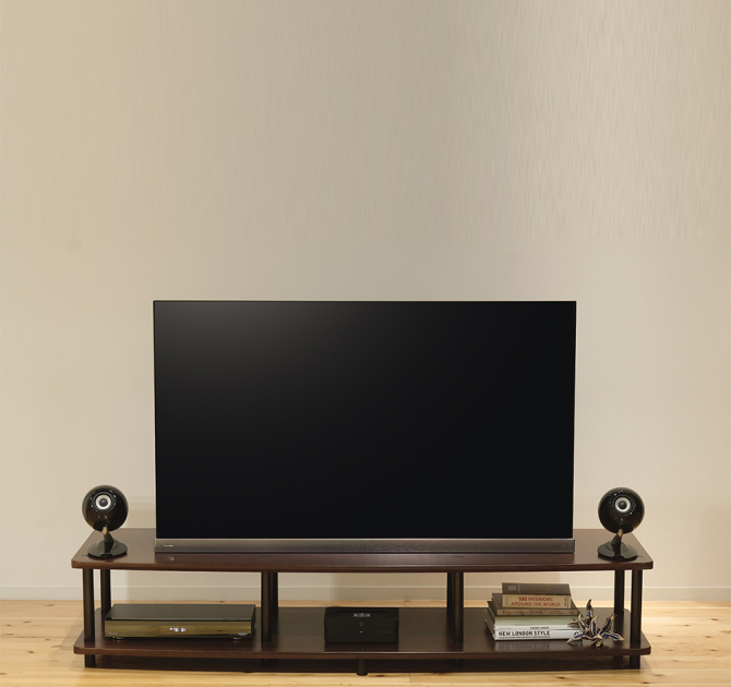A pair of Eclipse TD307MK3 Loudspeakers in black either side of a tv on a tv stand.
