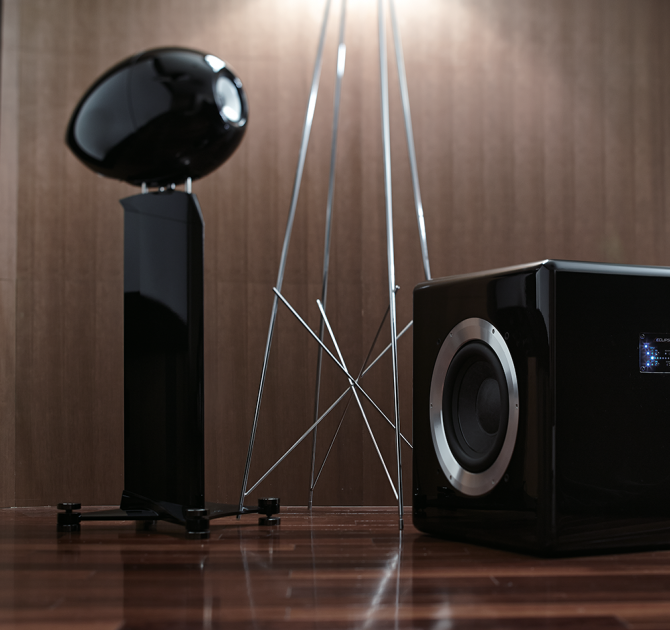 Eclipse TD725SWMK2 Subwoofer on a wooden floor with an Eclipse speaker.