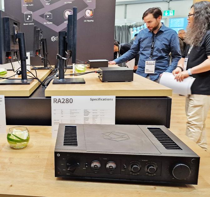 HiFi Rose RA280 in black on a wooden table with people in the background.  Photo taken at the Munich HiFi show in 2024