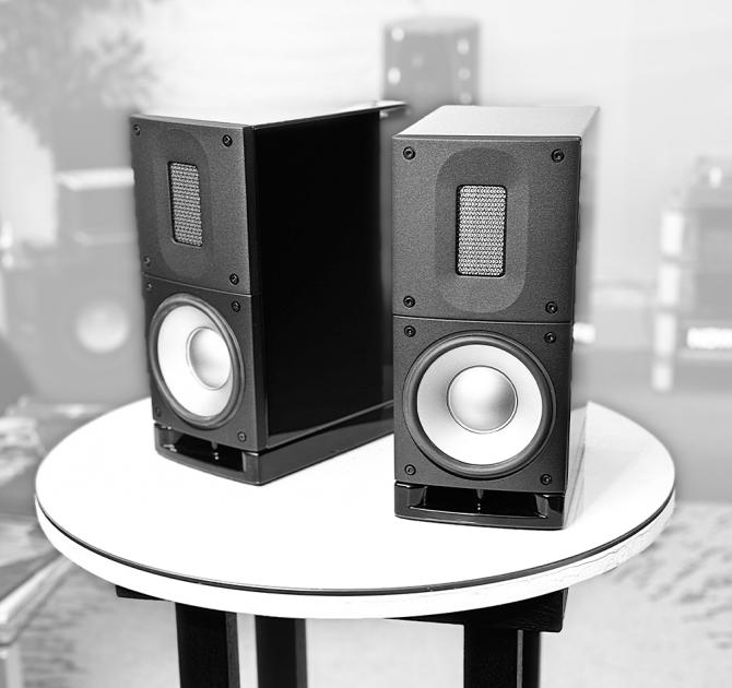 A pair of black Raidho Acoustics X1t Loudspeakers on a circular white table.  Black and white photo