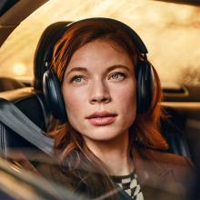 Sonos Ace Headphones in black on the head of a woman in a car