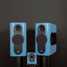 A pair of Kii Three Loudspeakers with the Kii Controller.  The speakers and the controller are a glossy blue colour