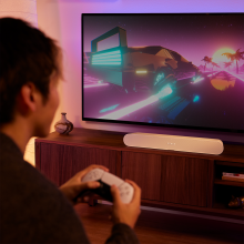 Sonos Ray Smart Soundbar in white with a partial view of a man gaming.