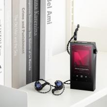 Astell & Kern A&ultima SP3000M Portable Music Player on a table with earphones beside it