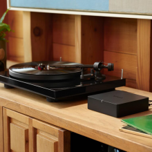 SONOS Port on a wooden unit with a record player to the left of it.