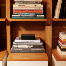 SONOS Port in a wooden modular shelving unit on top of a stack of books.