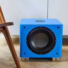 The REL T9x special edition in blue on a wooden floor beside a wooden chair