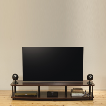 A pair of Eclipse TD307MK3 Loudspeakers in black either side of a tv on a tv stand.