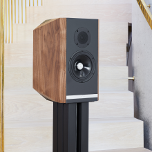 A single Titan 505 speaker with its grill off on a stand at the foot of a staircase.