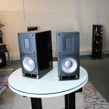 A pair of Raidho Acoustics X1t Loudspeakers on a circular white table.